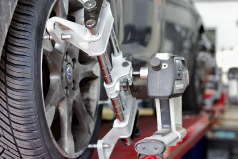 Een automonteur lijnt alle wielen uit van de auto in de garage